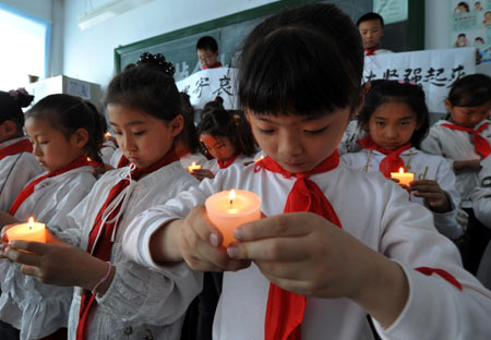 Pupils holding candles mourn during a silent tribute in Harbin, capital of northeast China&apos;s Heilongjiang Province, May 19, 2008.