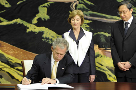  U.S. President George W. Bush (L) leaves words on the book of condolence as his wife Laura Bush (C) and Chinese Ambassador to the U.S. Zhou Wenzhong look on at the Chinese Embassy in Washington May 20, 2008. Bush came to the Chinese Embassy on May 20 to mourn Chinese quake victims.