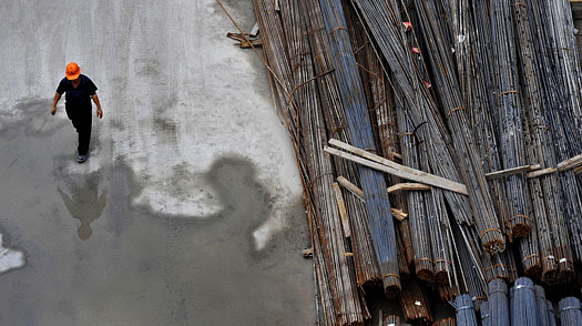 A construction worker walks past steel rods at a building site in Shanghai
on July 27, 2009